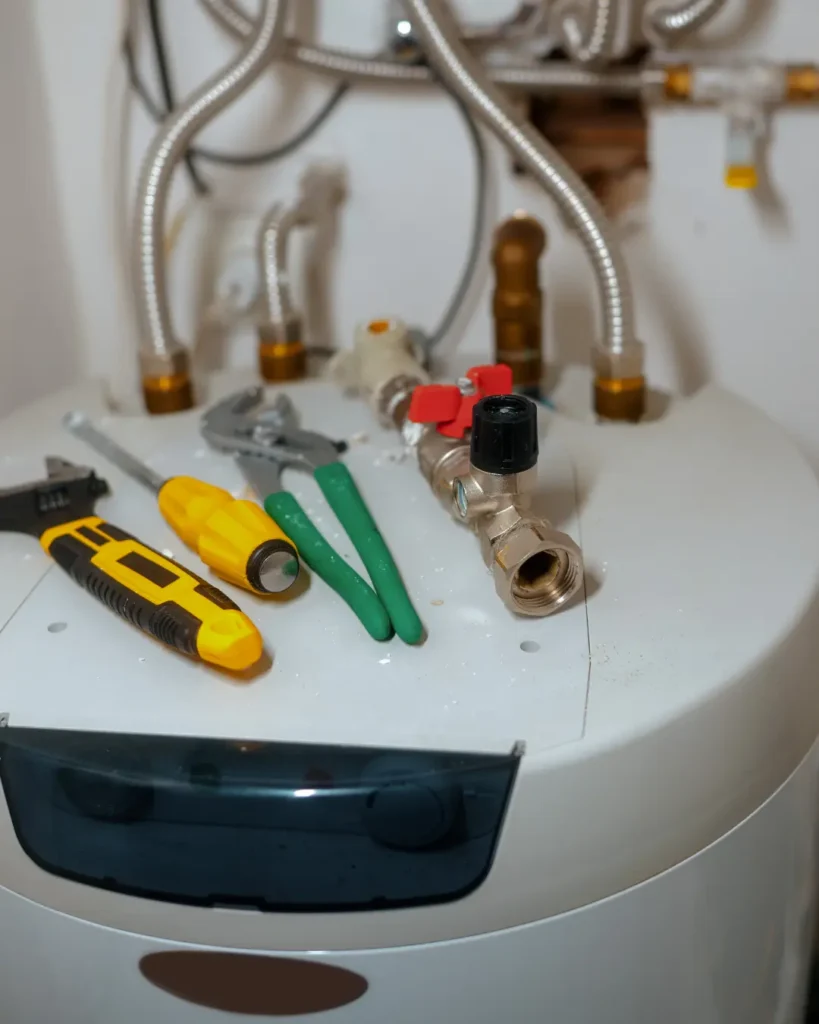 Top of a newly installed storage tank water heater showing flex connectors, shutoff valve, and expansion fittings