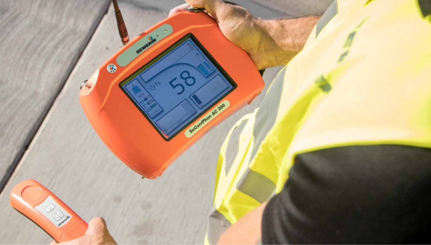 Plumber using an electronic leak locator to trace a water line
