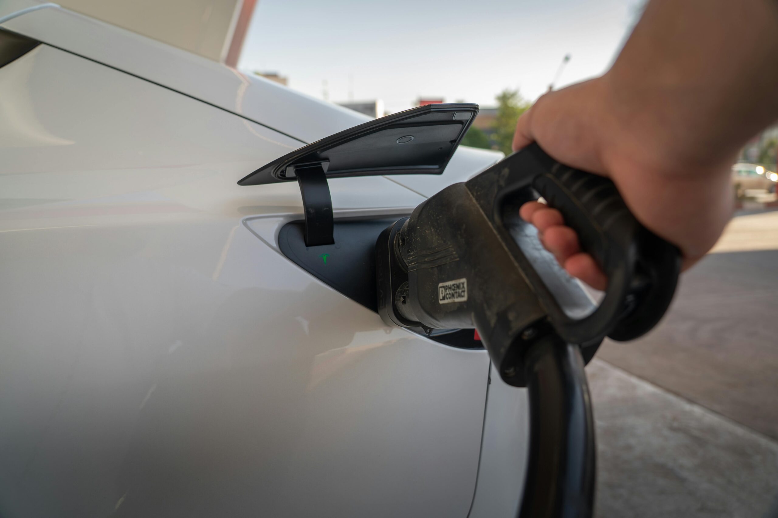 Hand plugging an electric vehicle charger into a charging port.
