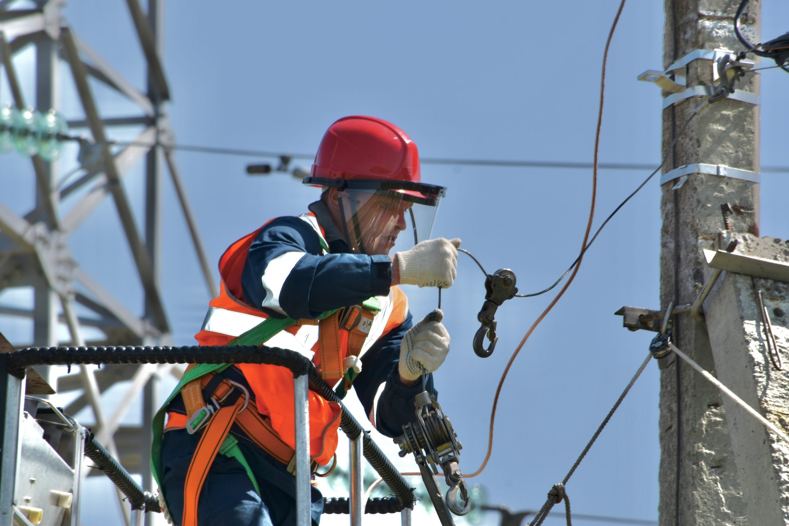 An electrician works on overhead power lines from an aerial lift bucket.