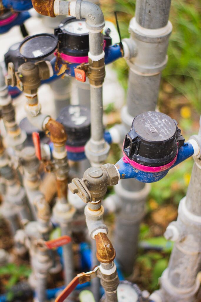 Aging galvanized water pipes and meters showing corrosion at the fittings on an older residential plumbing system